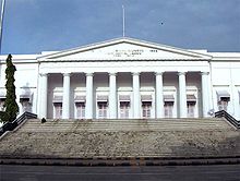 A white building with a triangular fa&ccedil;ade and wide stairs