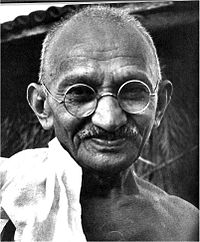 The face of Gandhi in old age&mdash;smiling, wearing glasses, and with a white sash over his right shoulder